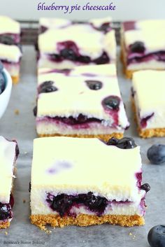 blueberry cheesecake bars are cut into squares and placed next to bowls of fresh berries