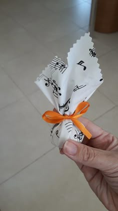 someone is holding some kind of paper with musical notes on it and an orange ribbon