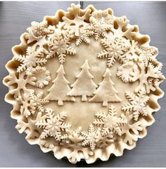 a pie crust decorated with snowflakes and trees