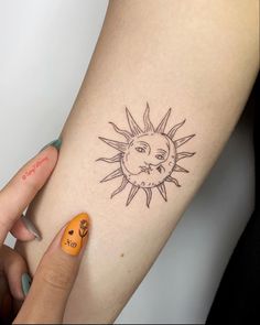 a woman's arm with a sun and moon tattoo on the left side of her body