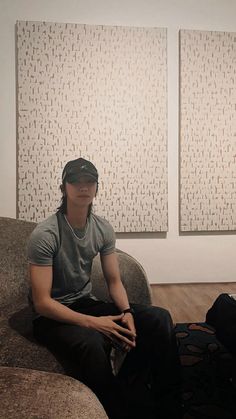 a man sitting on top of a couch in front of two large white wall paintings