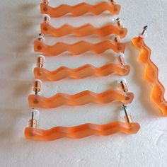 four orange plastic clips are lined up on a white surface