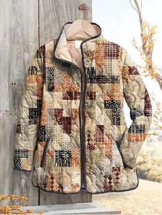 a quilted jacket hanging on the side of a wooden fence next to a tree