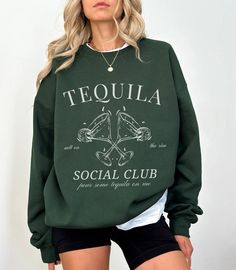 "Elevate your style with our exclusive Tequila-themed sweatshirt from Lavender Maple! This cozy crewneck sweater features a striking black and white design, showcasing the word \"Tequila\" in a bold varsity font on the front. Perfect for tequila enthusiasts and fashion-forward individuals alike, this statement piece not only keeps you warm but also adds a touch of vibrant personality to your wardrobe. Indulge in the comfort of this high-quality sweatshirt while expressing your love for tequila in a fashionable way. Ideal for casual outings, gatherings, or simply lounging at home with a drink in hand. Make a bold statement with our Tequila Sweatshirt and let your style speak volumes. Explore the intersection of comfort and fashion with Lavender Maple's exclusive apparel collection. Shop now Luxury Bachelorette, Vodka Martini, Cocktail Club, Club Sweatshirts, Dirty Martini, Espresso Martini, Signature Cocktail, Girls Club, Bridal Party Gifts