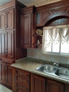 a kitchen with wooden cabinets and granite counter tops, along with a window over the sink