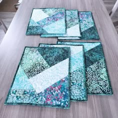 four quilted placemats sitting on top of a wooden table