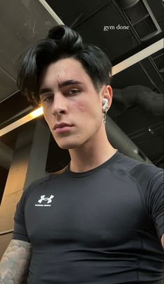 a man with black hair and piercings is looking at the camera