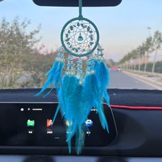 a car dashboard with a blue dream catcher hanging from the dash