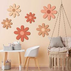 a baby's room with pink and orange flowers on the wall, hanging from a rope