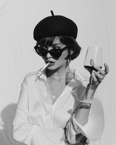 black and white photograph of a woman wearing sunglasses holding a wine glass in her right hand