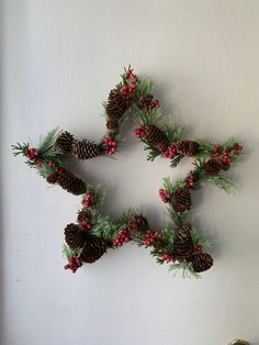 pine cones and berries are arranged in the shape of a star on a white wall