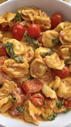 a white bowl filled with pasta and tomatoes