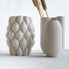 three white vases sitting next to each other on a table