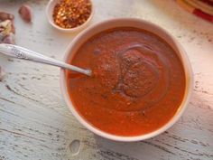 there is a bowl of soup on the table with two spoons next to it