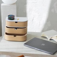 an apple laptop sitting on top of a table next to a wooden box with a ring in it