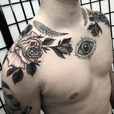 a close up of a man's chest with flowers and an eye on it