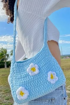 a woman is holding a crocheted purse with flowers on the front and side