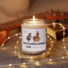 a candle that is sitting on a table next to some string lights and a ukulele