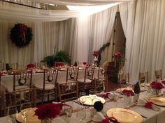 a banquet room set up with white linens and red flowers