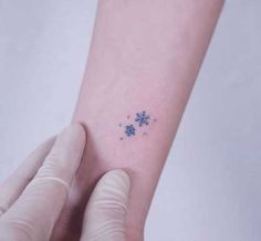 a person's arm with a small snowflake tattoo on the left wrist