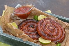 two hot dogs with ketchup and limes in a tray on a table