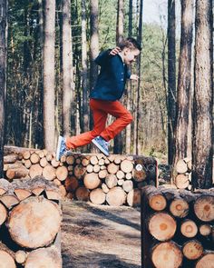 a boy jumping over logs in the woods