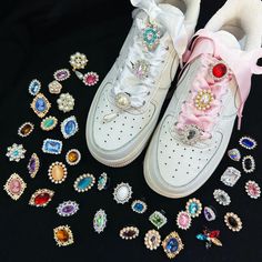 a pair of white sneakers sitting on top of a pile of brooches and earrings