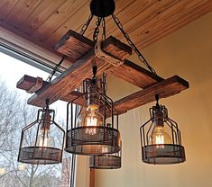 three lights hanging from a wooden beam in front of a window with wood beams on the ceiling