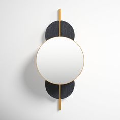 a round mirror mounted to the side of a wall next to a black and gold pole