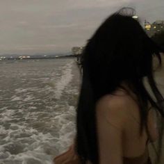 a woman standing on the back of a boat looking out at the water with buildings in the background