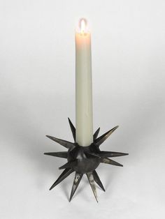 a candle with spikes on it sitting in front of a white background and the light is lit