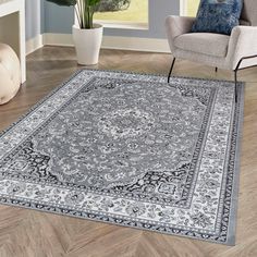 a large rug with an ornate design on the floor in a living room next to a chair and potted plant