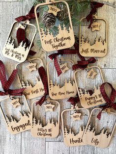 wooden christmas ornaments with pine trees and plaid ribbon on the top, hanging from a tree branch