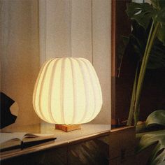 a white lamp sitting on top of a table next to a plant