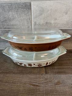 two casserole dishes stacked on top of each other in front of a wooden wall