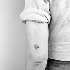 a person with a small sun tattoo on their left arm and the sun behind them