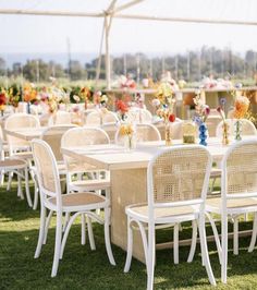 tables and chairs are set up in the grass for an outdoor wedding reception with floral centerpieces