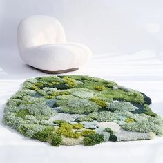 a white chair sitting on top of a rug covered in green and white mossy plants