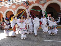 some people are dancing with colorful ribbons on their heads and dresses in the shape of flowers