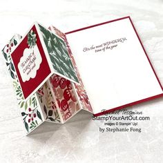 an open christmas card with holly and berries on the inside, sitting on a white surface