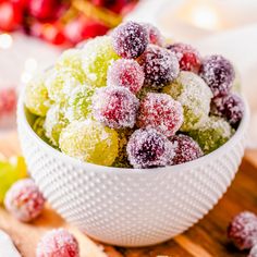 a white bowl filled with powdered sugar covered cranberries on top of a wooden cutting board