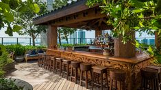 an outdoor bar with lots of stools next to trees and plants on the roof