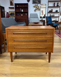 a wooden dresser sitting on top of a hard wood floor next to a blue chair