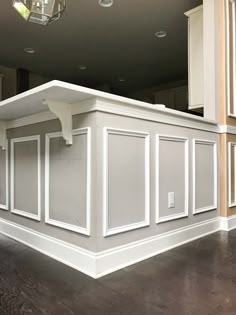 an empty kitchen with white cabinets and wood flooring in the middle of the room