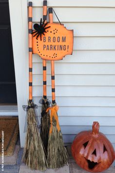 two brooms and a jack - o'- lantern sit on the front porch