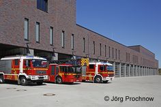 two fire trucks parked next to each other in front of a brick building with windows