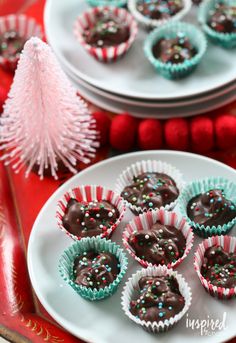 some chocolates are sitting on plates next to a christmas tree