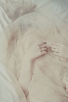 a woman laying in bed under a white blanket