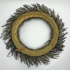 a wicker wreath with dried lavenders on the front and sides, hanging on a white wall