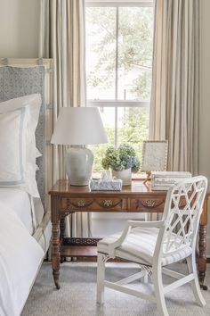 a white chair sitting next to a wooden desk with a lamp on top of it